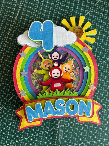 Colorful birthday cake topper with 'Teletubbies' characters and the name 'Mason' on a grid background.