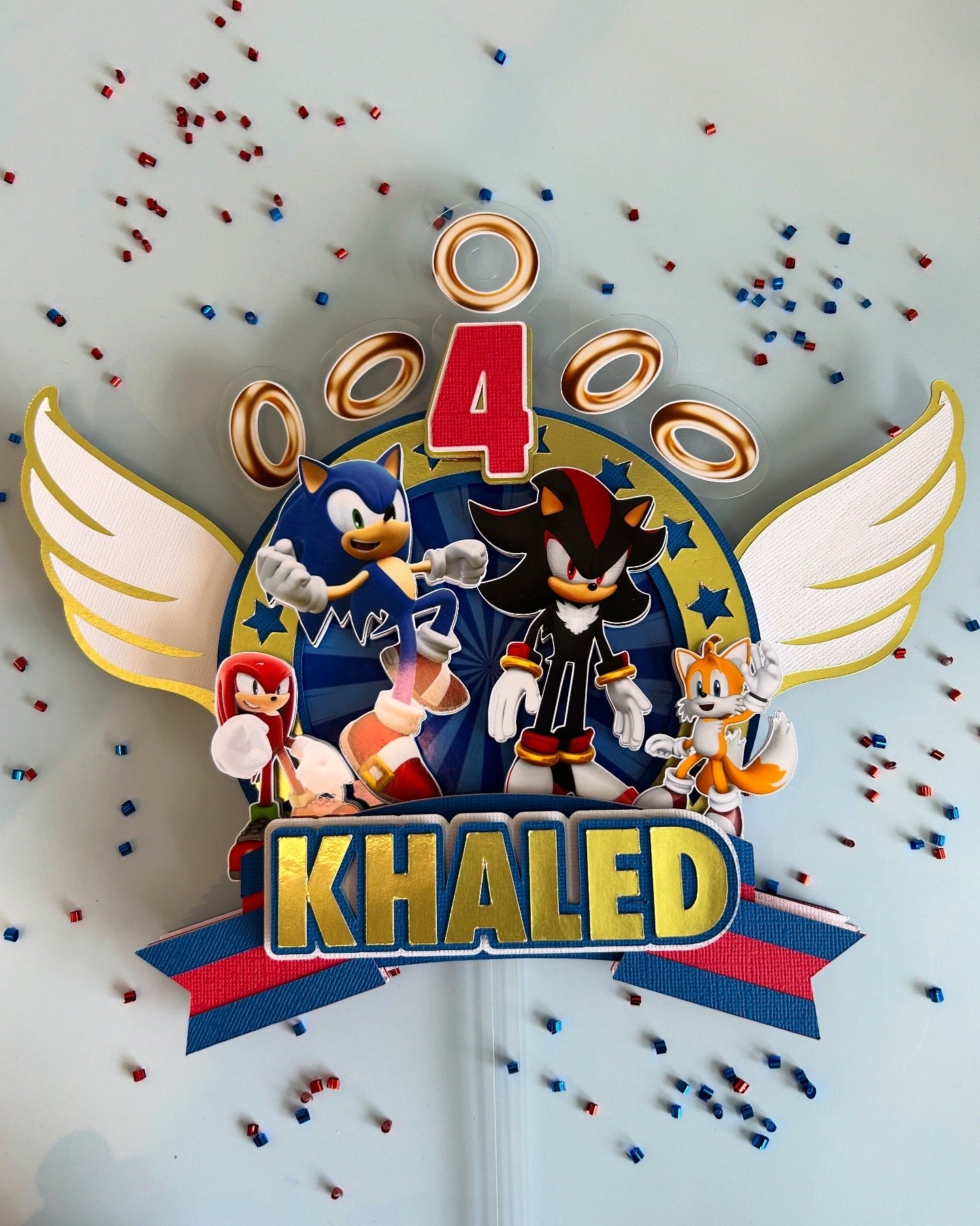 Personalized birthday cake topper with cartoon characters and 'Khaled' text on a light gray background.