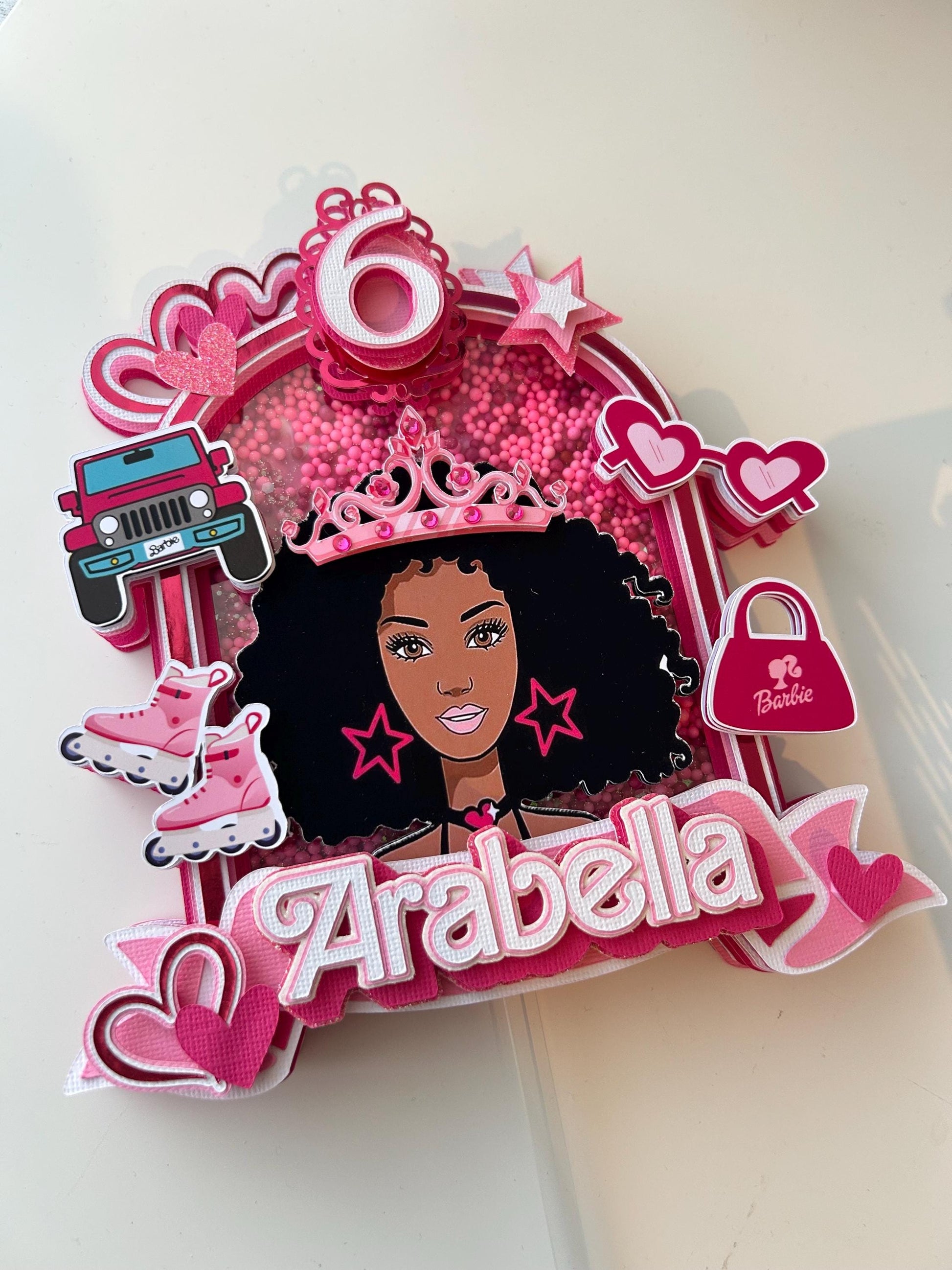 Decorative birthday cake topper with a girl's face, pink accents, and the name 'Arabella'.