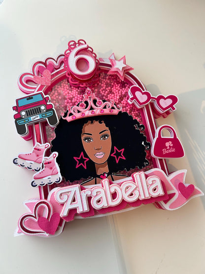 Decorative birthday cake topper with a girl's face, pink accents, and the name 'Arabella'.