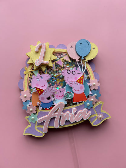 Decorative birthday cake topper with Peppa Pig characters and balloons on a pink background