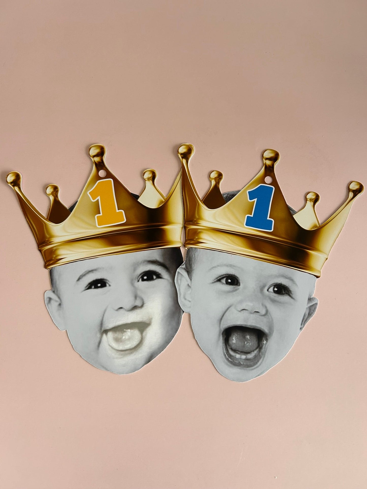 Two baby faces wearing gold crowns with blue and orange numbers on a beige background